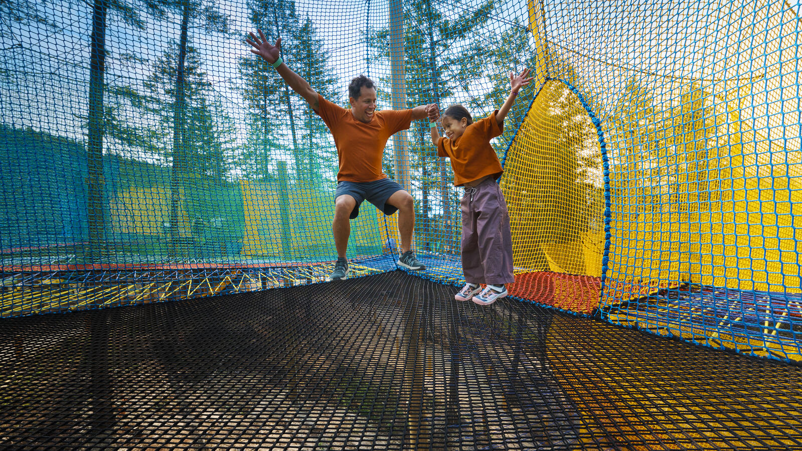 Adult and child jumping together on the new Eagle Net Park attraction at Golden Skybridge